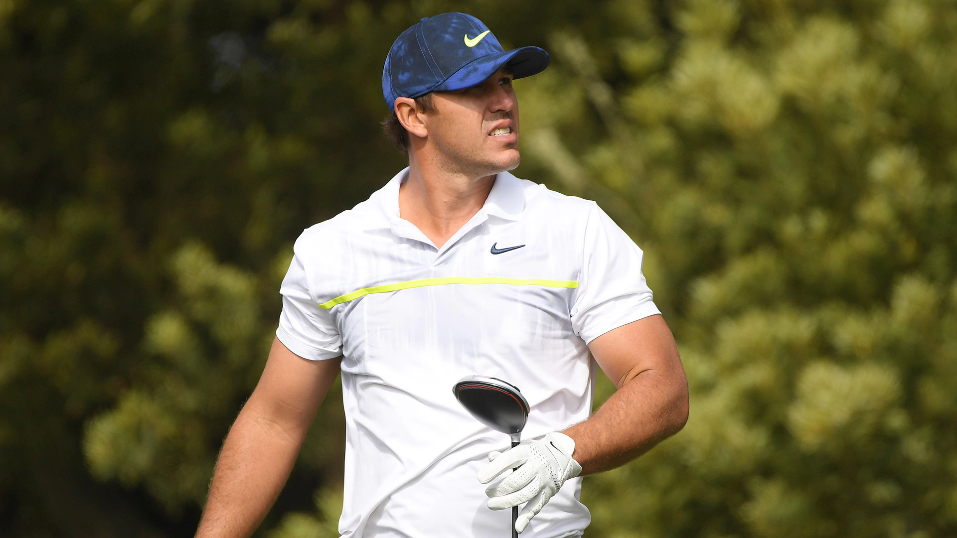 Brooks Koepka lays down in rough, has trainer stretch out his ailing left leg