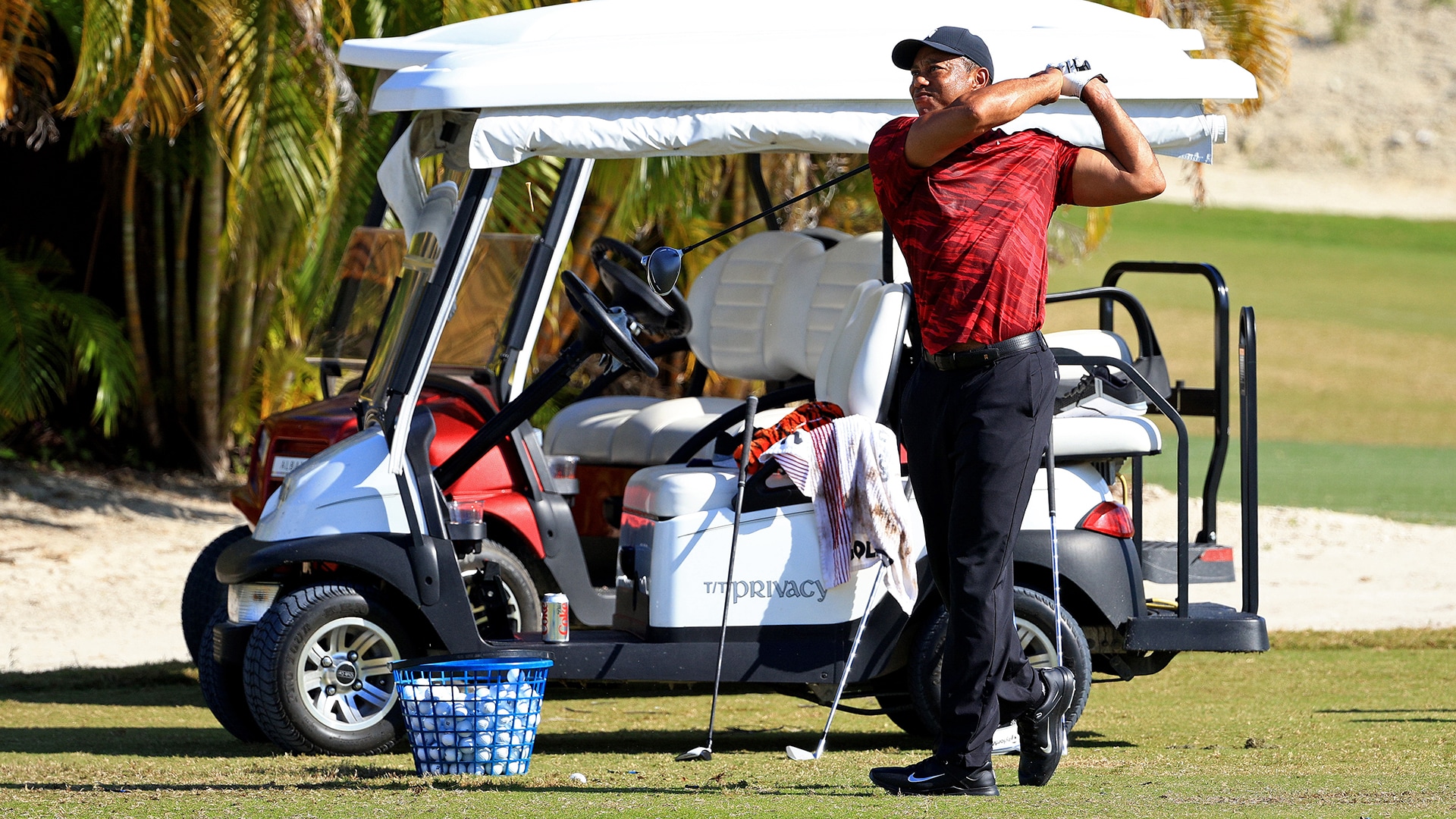 Wearing Sunday red, Tiger Woods hits balls yet again during Hero