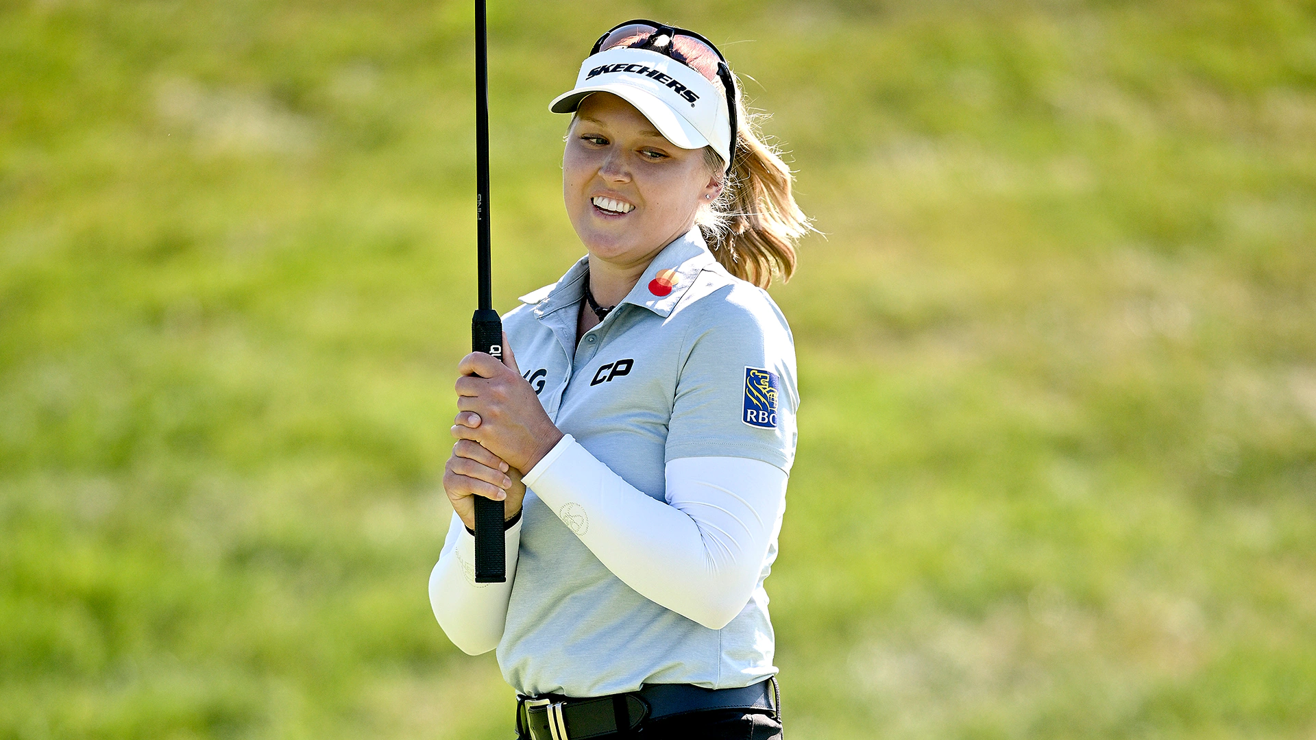 With left hand low, Brooke Henderson puts both hands on Evian trophy